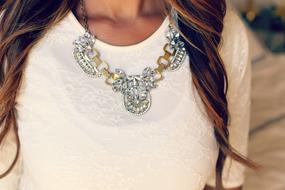 Close-up of the necklace with shapes, on the neck of the woman in white clothing