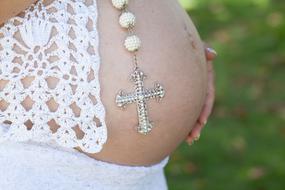 Close-up of the pregnant woman's belly with the cross on it