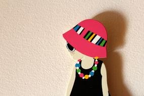 Model of the girl with colorful necklace, hat and sunglasses, near the wall with shadow