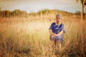 Elderly woman, in front of a field