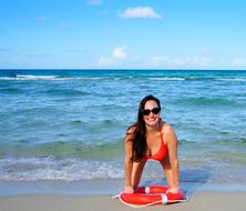 girl in a red bikini with a lifebuoy on the beach