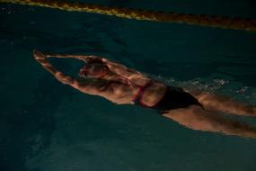 woman swims underwater in the pool in a fitness club