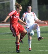 women in red and white uniforms play football