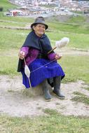 Smiling, sitting woman with a spinner on beautiful Andes, Ecuador