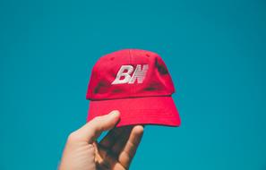 red Cap in hand at blue sky