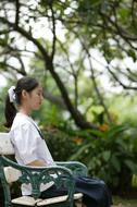 Profile portrait of a posing girl on the bench among the beautiful and colorful plants in Thailand