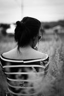 back view of woman sitting among Grass