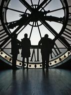 silhouettes of people on the background of a tower clock