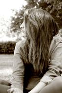 Black and white profile portrait of a girl, among the plants, with the hair covering her face