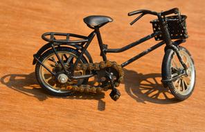 Model of the shiny, black bike on the brown ground, in light