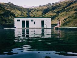 girl sits at Swimming pool in view of scenic mountains