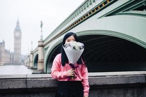 girl with a bouquet of flowers on the background of the bridge