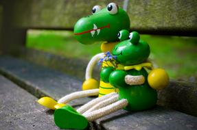 a pair of wooden toy frogs on a bench