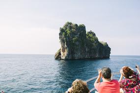 People on boat looking at scenic rock formation in sea