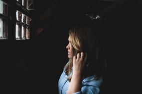 portrait of long haired Woman at window in darkness