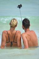 couple in the ocean is taking selfie