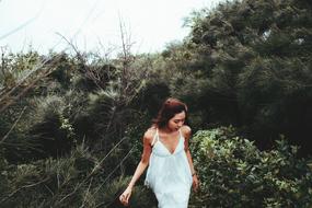 girl in white posing in green thickets