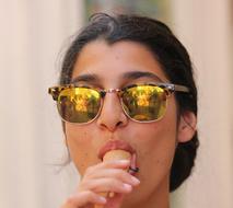 portrait of Girl in golden glossy Glasses eating