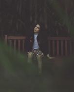 young girl sits on bench outdoor at dusk