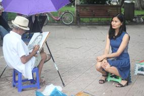senior man drawing portrait of asian girl outdoor