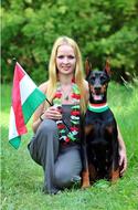 pretty girl with hungarian flag and doberman dog posing on grass, sports fans