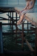 girl in a striped dress sitting on a pier