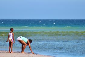 woman with child collect seashells on the beach