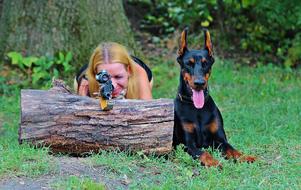girl with guns next to the doberman