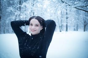 girl in a black sweater on a background of a snowy park