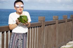 Girl on the pier with coconut cocktail in Asia