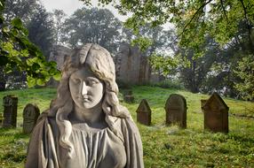 aged stone sculpture on cemetery, mourning Woman