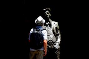 a man stands near a statue in the dark