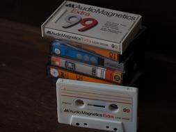 Old and colorful cassettes in the stack, at black background