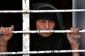 elderly muslim Woman behind grates, Iraq