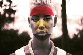 portrait of a fan with flag colors on her face on a blurred background