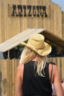 back view of girl in cowboy hat near wooden building with Arizona sign