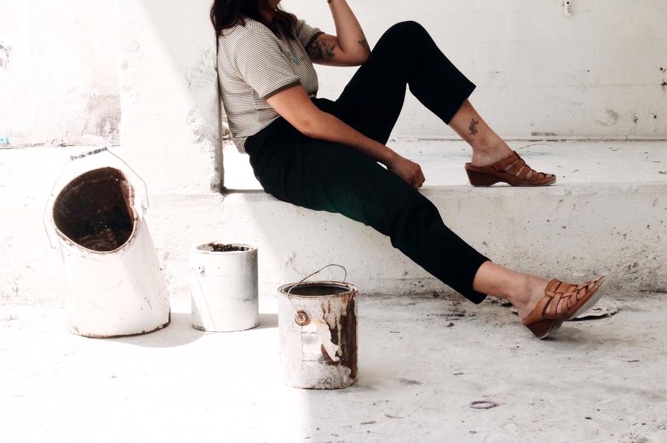 unrecognizable Woman in black pants sits at wall