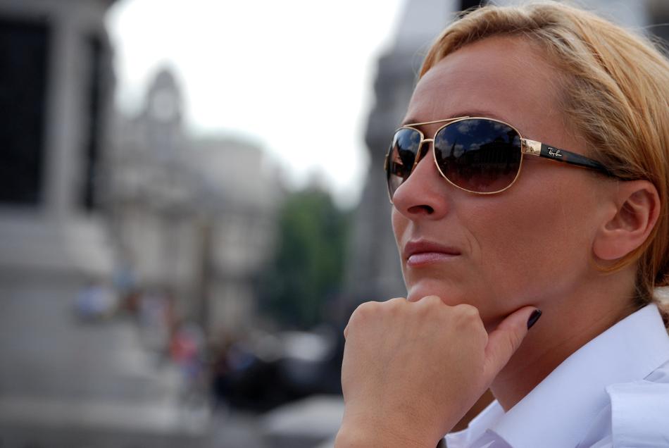 Portrait of the blonde woman with sunglasses, at blurred background with the city