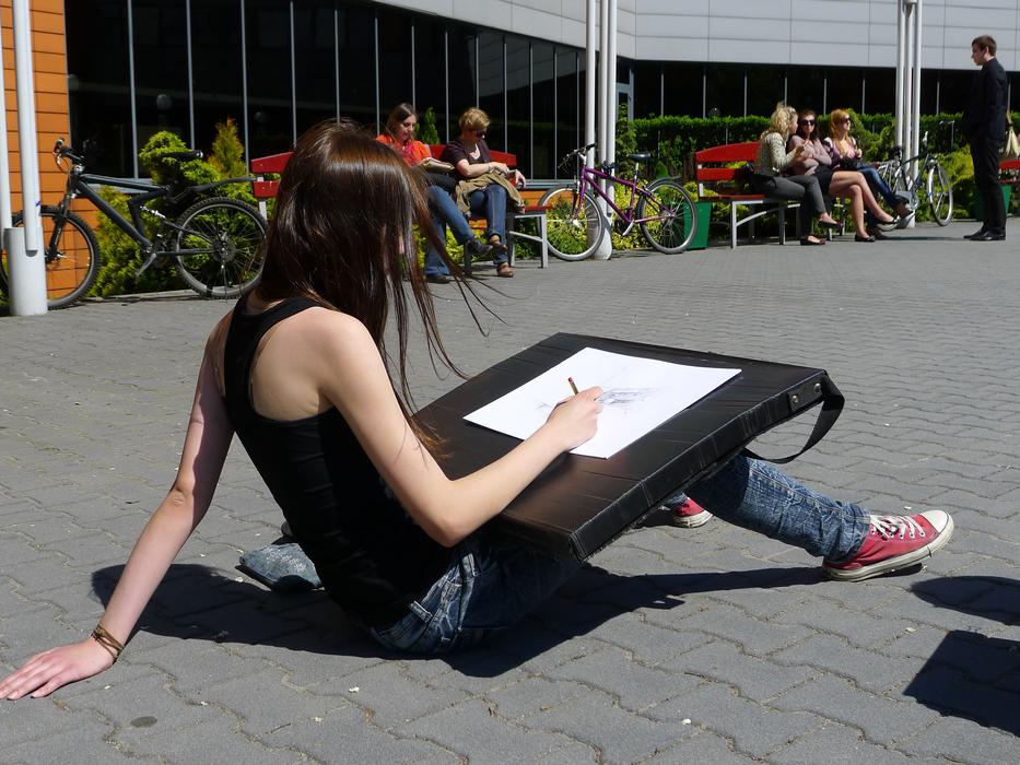Girl making pencil drawing in city, Poland