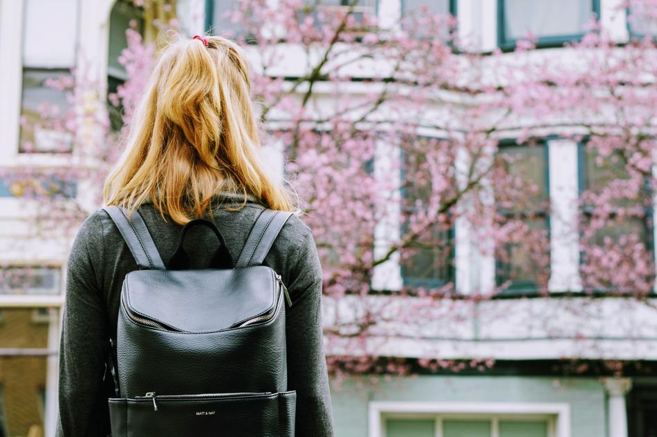 girl with a leather backpack on the background of the building