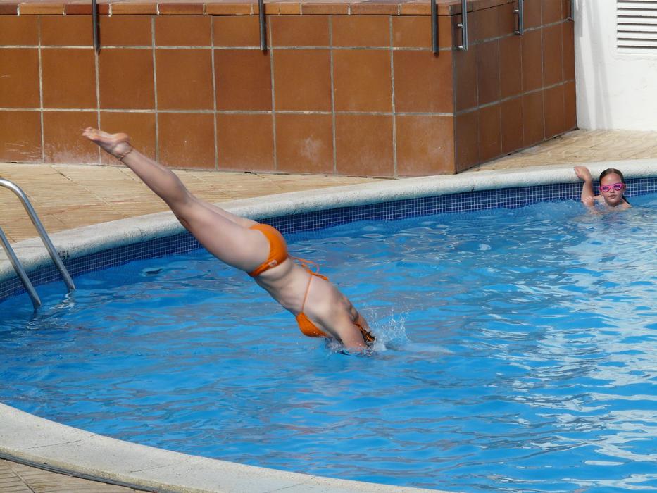 girl in orange bikini jumping into the pool