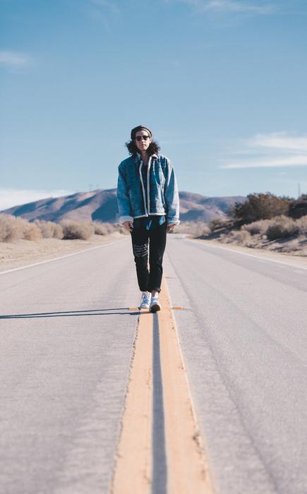 a man walks alone along the median strip of the highway