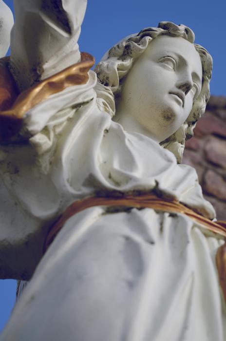 Beautiful, white and gold sculpture of the woman, at blue sky on background