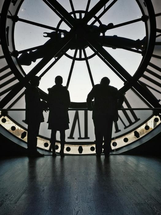 silhouettes of people on the background of a tower clock