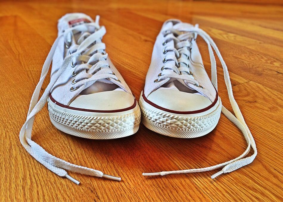 pair of white Converse Sneakers on wooden floor
