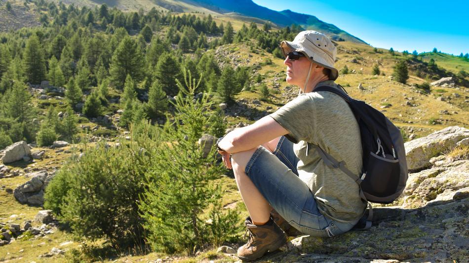 woman with a backpack sits on a mountainside
