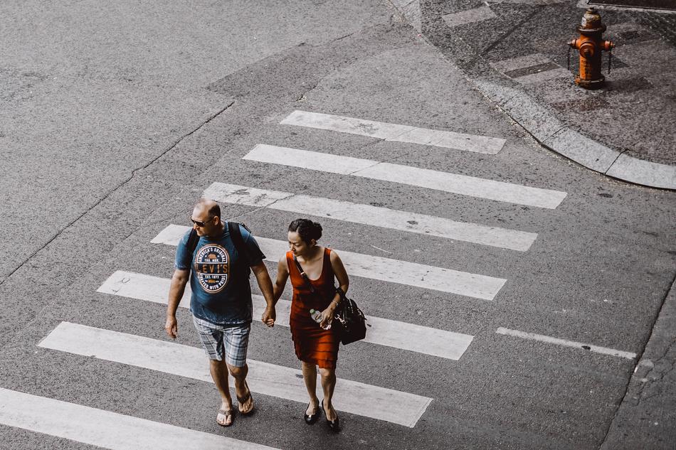 couple holding hands and walking along the crosswalk