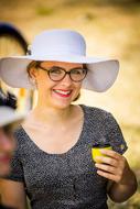 young happy woman in white wide hat with cup in hand