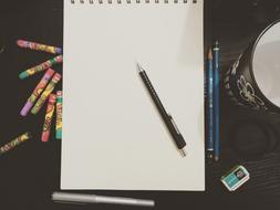 Pen, pencils and crayons at empty Paper