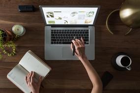 girl works on a laptop and writes in a notebook